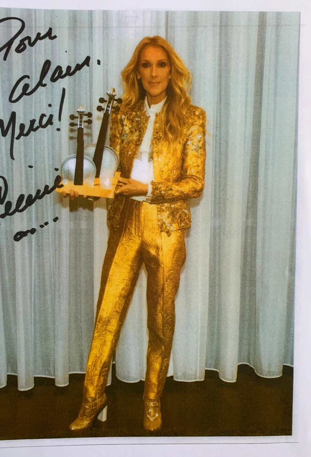 Photographie dédicacée « Pour Alain, merci ! » : Céline Dion tenant une sculpture Tikoun Olam à deux instruments